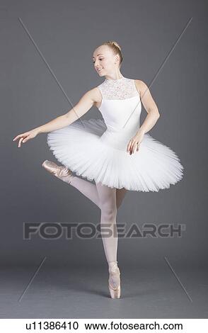 Young female ballet dancer dancing over grey background View Large Photo Image Stock Image - Young female ballet dancer dancing over grey background. Fotosearch