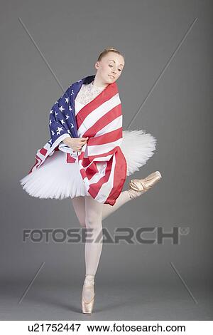 Stock Photo - Young female ballet dancer dancing wearing American flag over grey background. Fotosearch