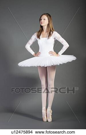 Young female ballet dancer tiptoeing against grey background View Large Photo Image Picture - Young female ballet dancer tiptoeing against grey background. Fotosearch