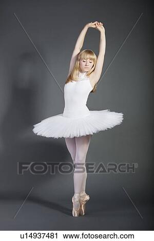 Young female ballet dancer tiptoeing over grey background View Large Photo Image Stock Image - Young female ballet dancer tiptoeing over grey background. Fotosearch