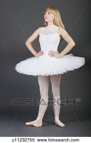 Young female ballet dancer with hands on hips standing over grey background View Large Photo Image Stock Photography - Young female ballet dancer with hands on hips standing over grey background. Fotosearch