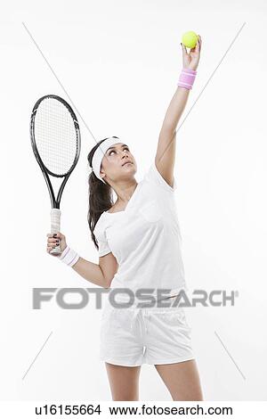 Picture - Young female tennis player preparing to serve ball against white background. Fotosearch