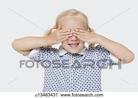 Stock Image - Young girl covering her eyes over white background. Fotosearch