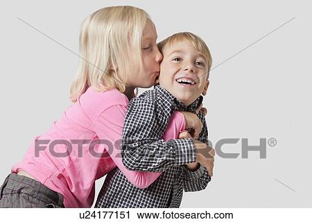 Stock Image - Young girl kissing and embracing brother over white background. Fotosearch