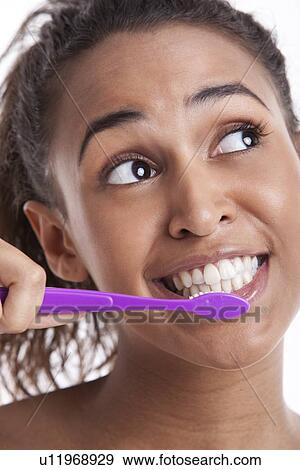 Young Mixed Race woman brushing teeth against white background View Large Photo Image Stock Photo - Young Mixed Race woman brushing teeth against white background. Fotosearch