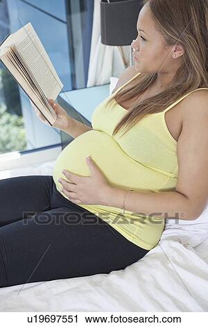 Young pregnant woman reading book while relaxing on bed at home View Large Photo Image Stock Image - Young pregnant woman reading book while relaxing on bed at home. Fotosearch