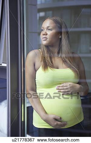 Young pregnant woman with hands on stomach looking away View Large Photo Image Stock Photo - Young pregnant woman with hands on stomach looking away. Fotosearch