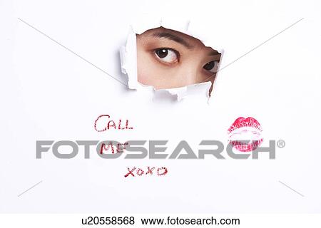Stock Photo - Young woman peeking through ripped paper with text message and lipstick mark. Fotosearch