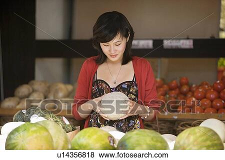 Young woman selecting melon in food market View Large Photo Image Stock Photo - Young woman selecting melon in food market. Fotosearch