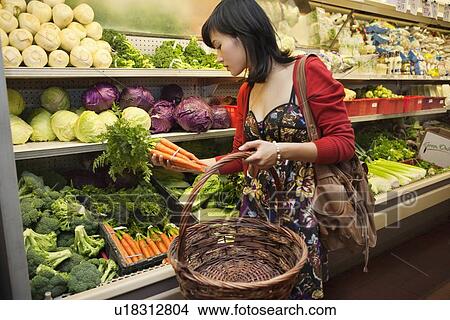 Picture - Young woman shopping for vegetables in farmer's market. Fotosearch