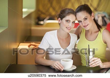 Stock Photography - Young woman sitting with friend at cafe. Fotosearch
