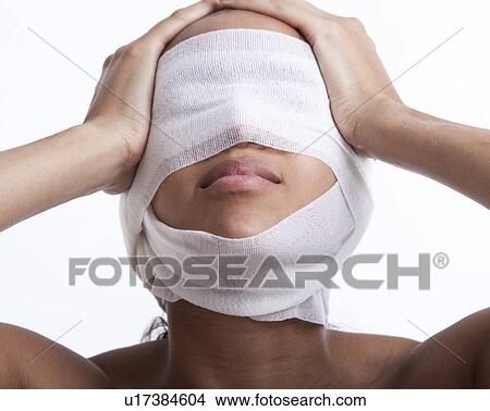 Picture - Young woman with head wrapped in bandage against white background. Fotosearch