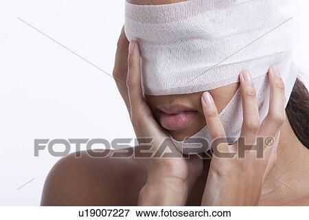 Stock Photo - Young woman with head wrapped in bandage against white background. Fotosearch
