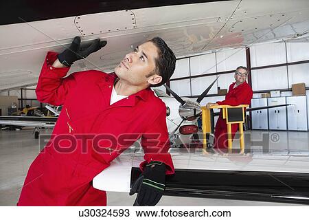 Aeronautical engineers working in airplane hangar View Large Photo Image Stock Image - Aeronautical engineers working in airplane hangar. Fotosearch