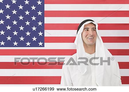 An Arab man in traditional clothes looking away against American flag View Large Photo Image Stock Photo - An Arab man in traditional clothes looking away against American flag. Fotosearch