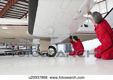 Aviation mechanics inspecting airplane wing View Large Photo Image Stock Photo - Aviation mechanics inspecting airplane wing. Fotosearch