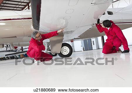 Aviation mechanics inspecting airplane wing View Large Photo Image Stock Photo - Aviation mechanics inspecting airplane wing. Fotosearch
