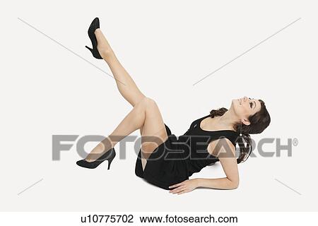 Beautiful young woman in dress sitting on floor with feet up against white background View Large Photo Image Stock Image - Beautiful young woman in dress sitting on floor with feet up against white background. Fotosearch