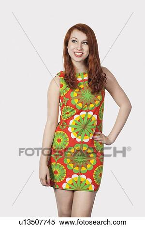 Stock Photography - Beautiful young woman in multicolored dress posing against gray background. Fotosearch