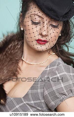 Beautiful young woman with veiled hat and fur boa against blue background View Large Photo Image Stock Photo - Beautiful young woman with veiled hat and fur boa against blue background. Fotosearch