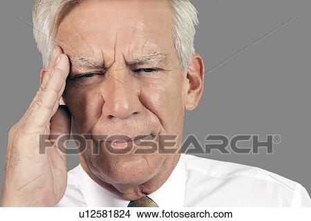 Close-up of a businessman suffering from headache over gray background View Large Photo Image Picture - Close-up of a businessman suffering from headache over gray background. Fotosearch