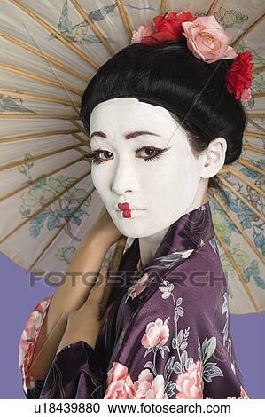 Close-up of Japanese woman with painted face holding parasol against purple background View Large Photo Image Stock Image - Close-up of Japanese woman with painted face holding parasol against purple background. Fotosearch