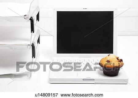 Cupcake and laptop beside office paper rack View Large Photo Image Stock Photo - Cupcake and laptop beside office paper rack. Fotosearch