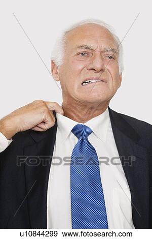 Elderly businessman holding collar feeling uncomfortable against white background View Large Photo Image Stock Photo - Elderly businessman holding collar feeling uncomfortable against white background. Fotosearch