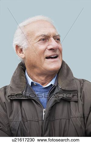 Elderly man looking away against blue background View Large Photo Image Stock Image - Elderly man looking away against blue background. Fotosearch