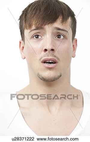 Stock Image - Fearful young man looking away over white background. Fotosearch
