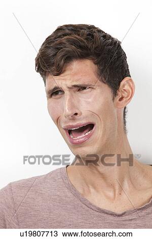 Frightened young man crying against white background View Large Photo Image Stock Image - Frightened young man crying against white background. Fotosearch
