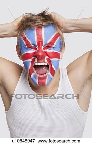Stock Photo - Frustrated young Caucasian man with British flag painted on face screaming against white background. Fotosearch