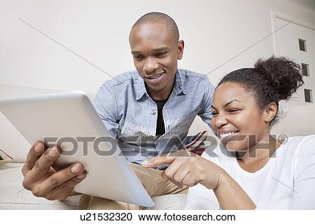 Happy African American young couple using tablet PC at home View Large Photo Image Stock Image - Happy African American young couple using tablet PC at home. Fotosearch