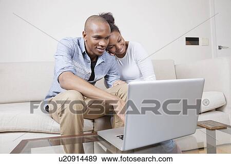 Happy African American young couple using laptop at home View Large Photo Image Stock Photo - Happy African American young couple using laptop at home. Fotosearch
