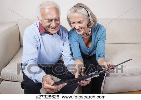 Happy senior couple looking at spiral book View Large Photo Image Stock Photograph - Happy senior couple looking at spiral book. Fotosearch