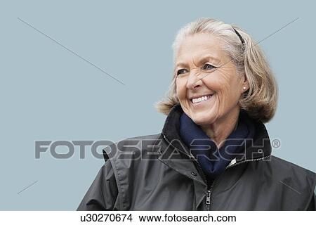 Happy senior woman looking away against blue background View Large Photo Image Picture - Happy senior woman looking away against blue background. Fotosearch
