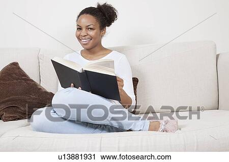 Happy young African American woman reading book on sofa View Large Photo Image Stock Image - Happy young African American woman reading book on sofa. Fotosearch