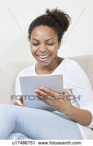 Stock Image - Happy young African American woman using tablet PC. Fotosearch