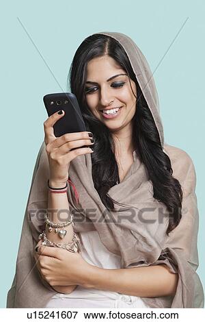 Happy young Asian woman in traditional clothing text messaging against blue background View Large Photo Image Stock Photo - Happy young Asian woman in traditional clothing text messaging against blue background. Fotosearch