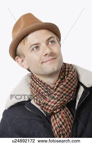 Happy young Caucasian man in warm clothing looking away against white background View Large Photo Image Stock Image - Happy young Caucasian man in warm clothing looking away against white background. Fotosearch