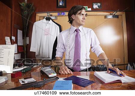 Stock Photo - Man at counter looking away in the launderette. Fotosearch
