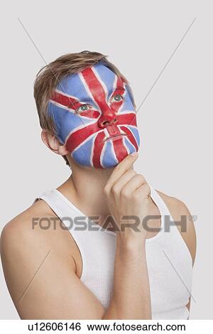Stock Photograph - Pensive young Caucasian man with British flag painted on face against white background. Fotosearch