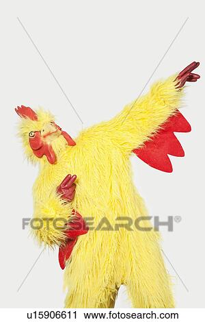 Playful young man in chicken suit against gray background View Large Photo Image Stock Image - Playful young man in chicken suit against gray background. Fotosearch