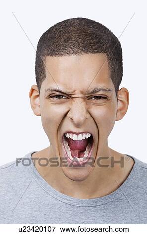 Portrait of aggressive young mixed race man screaming against white background View Large Photo Image Stock Photo - Portrait of aggressive young mixed race man screaming against white background. Fotosearch