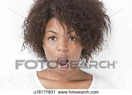 Stock Image - Portrait of amazed young woman with mouth open against white background. Fotosearch