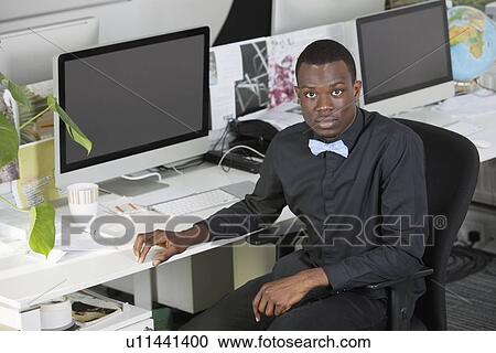 Portrait of an African American businessman sitting at desk in office View Large Photo Image Stock Image - Portrait of an African American businessman sitting at desk in office. Fotosearch