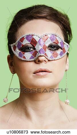Portrait of beautiful young woman wearing eye mask against green background View Large Photo Image Stock Image - Portrait of beautiful young woman wearing eye mask against green background. Fotosearch