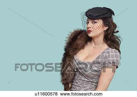 Stock Photo - Portrait of beautiful young woman with fur boa against blue background. Fotosearch