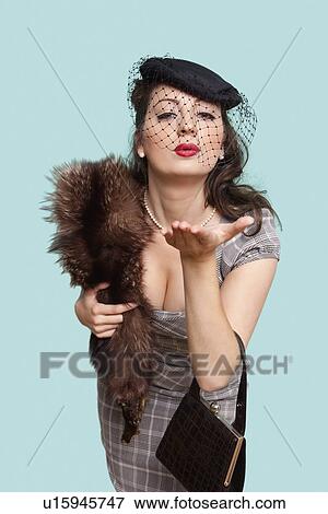 Portrait of beautiful young woman with fur boa blowing kisses against blue background View Large Photo Image Stock Photo - Portrait of beautiful young woman with fur boa blowing kisses against blue background. Fotosearch