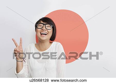 Portrait of cheerful young woman gesturing peace sign against Japanese flag View Large Photo Image Stock Photo - Portrait of cheerful young woman gesturing peace sign against Japanese flag. Fotosearch